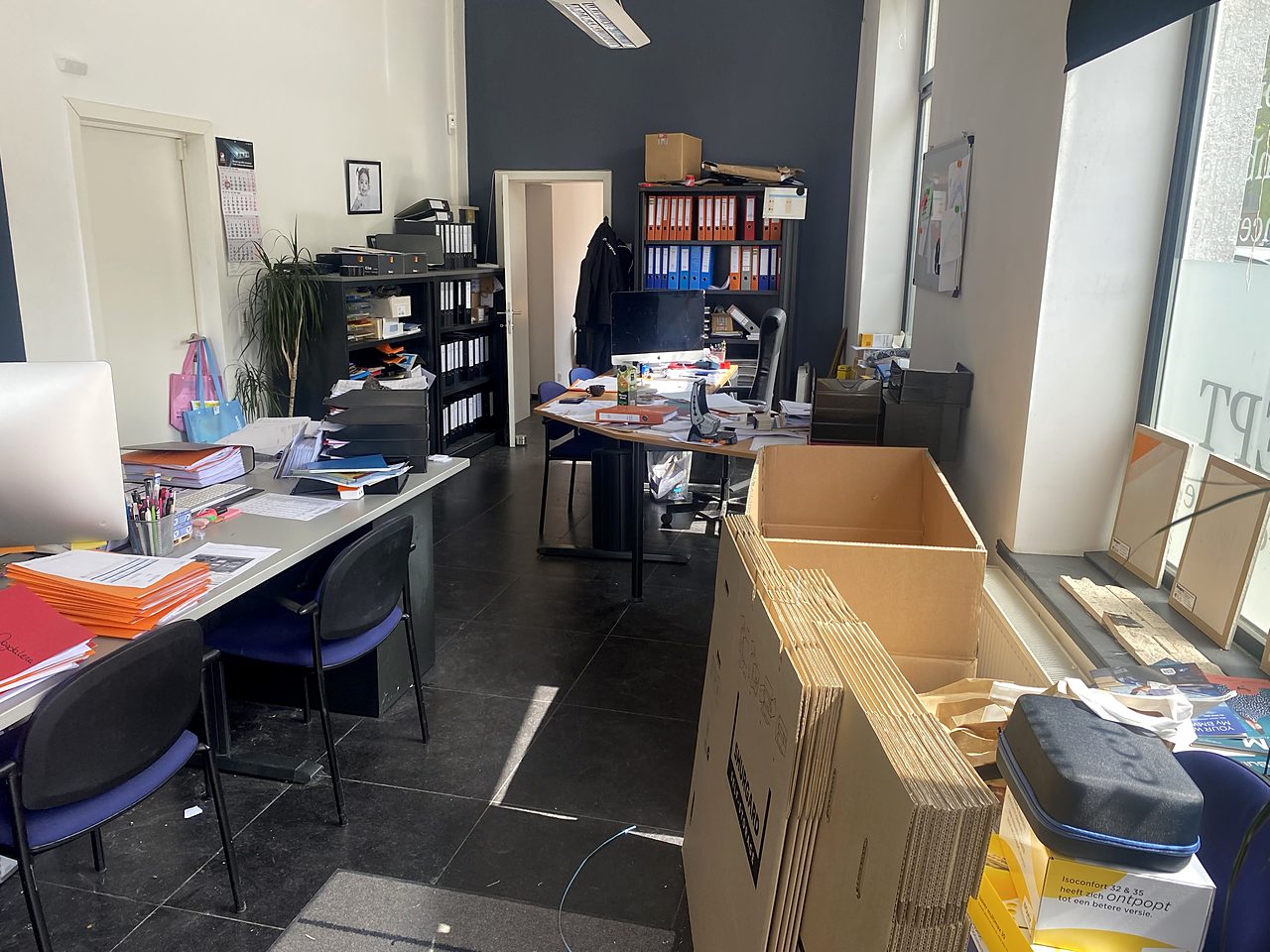 Bureau encombré de dossiers, de meubles et de cartons avant le débarras
